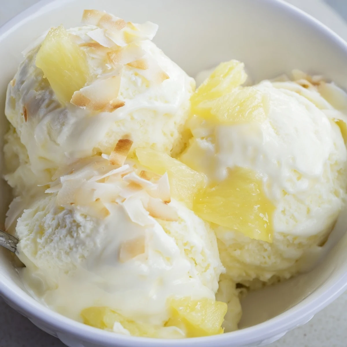 Scoops of Creamy Pineapple Ice Cream topped with toasted coconut, chilled  