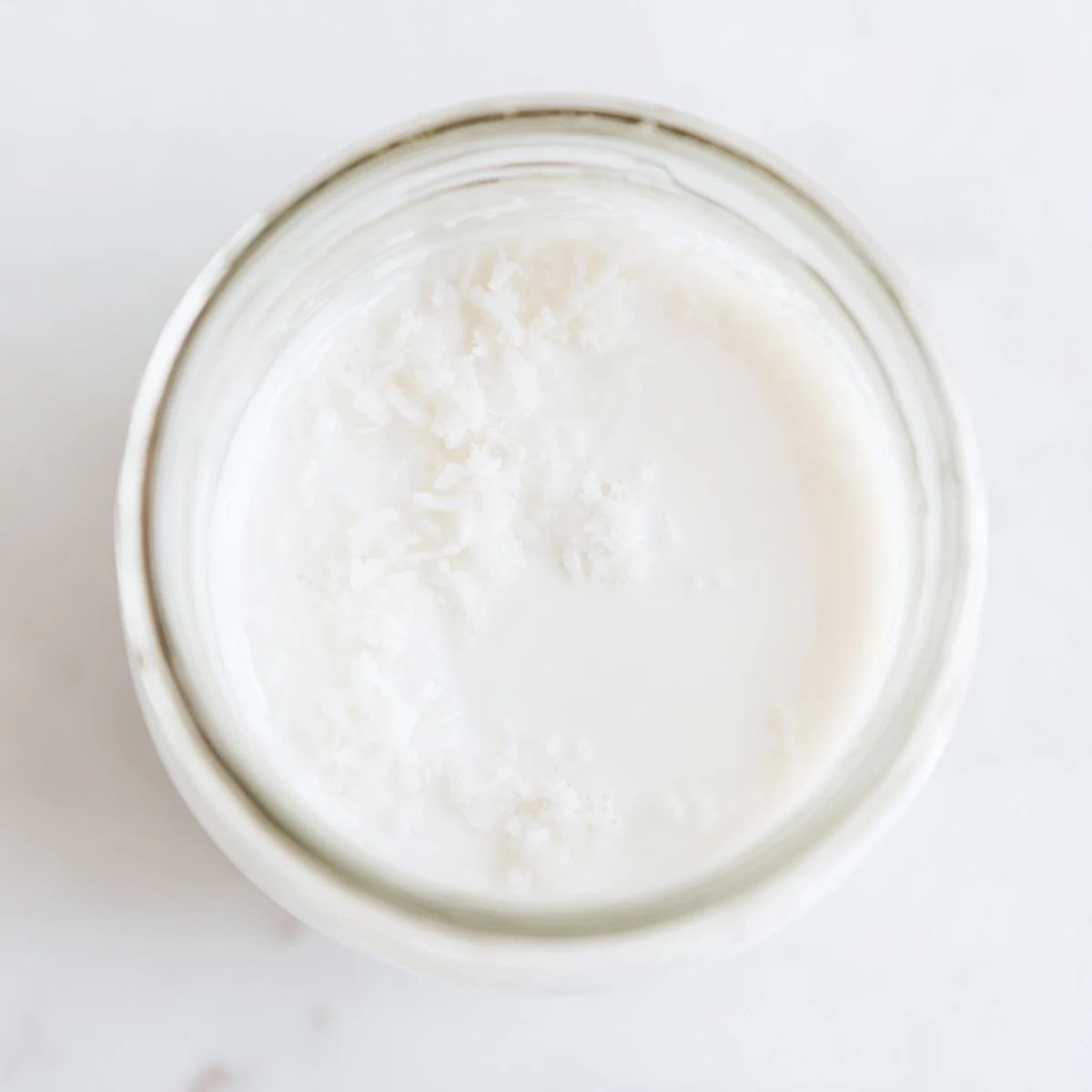 Silky smooth homemade coconut milk strained through nut milk bag into bowl
