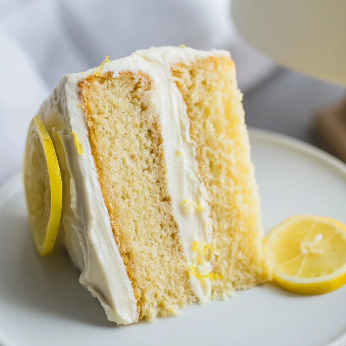 Bright lemon birthday cake slice showing moist yellow crumb topped with zesty cream cheese frosting