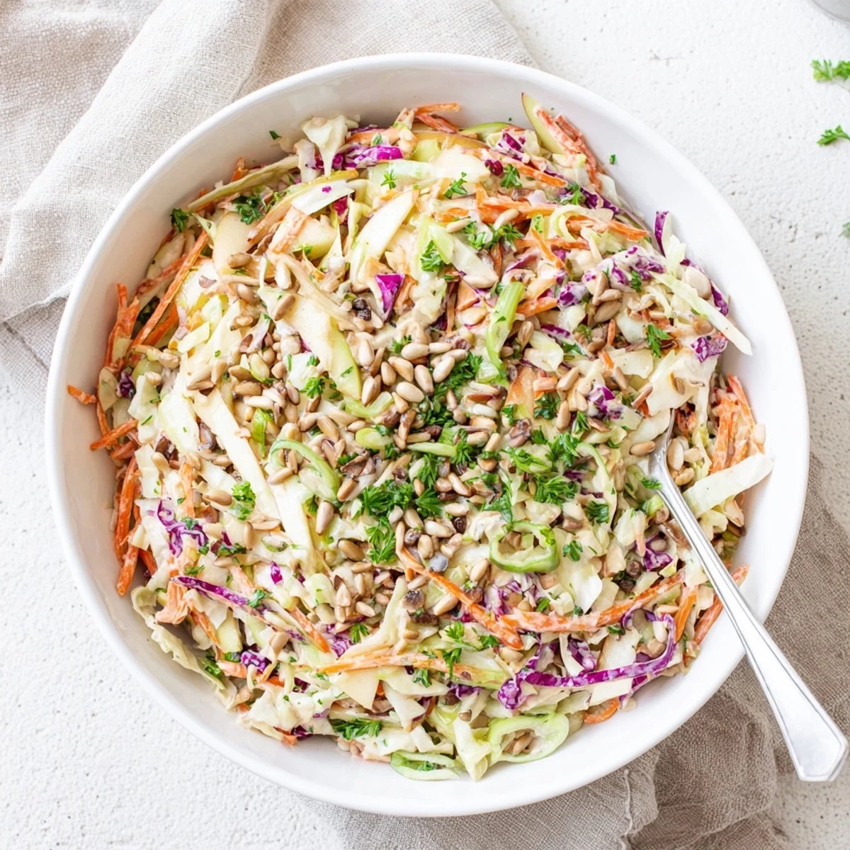 Colorful apple coleslaw topped with parsley and sunflower seeds for summer barbecues