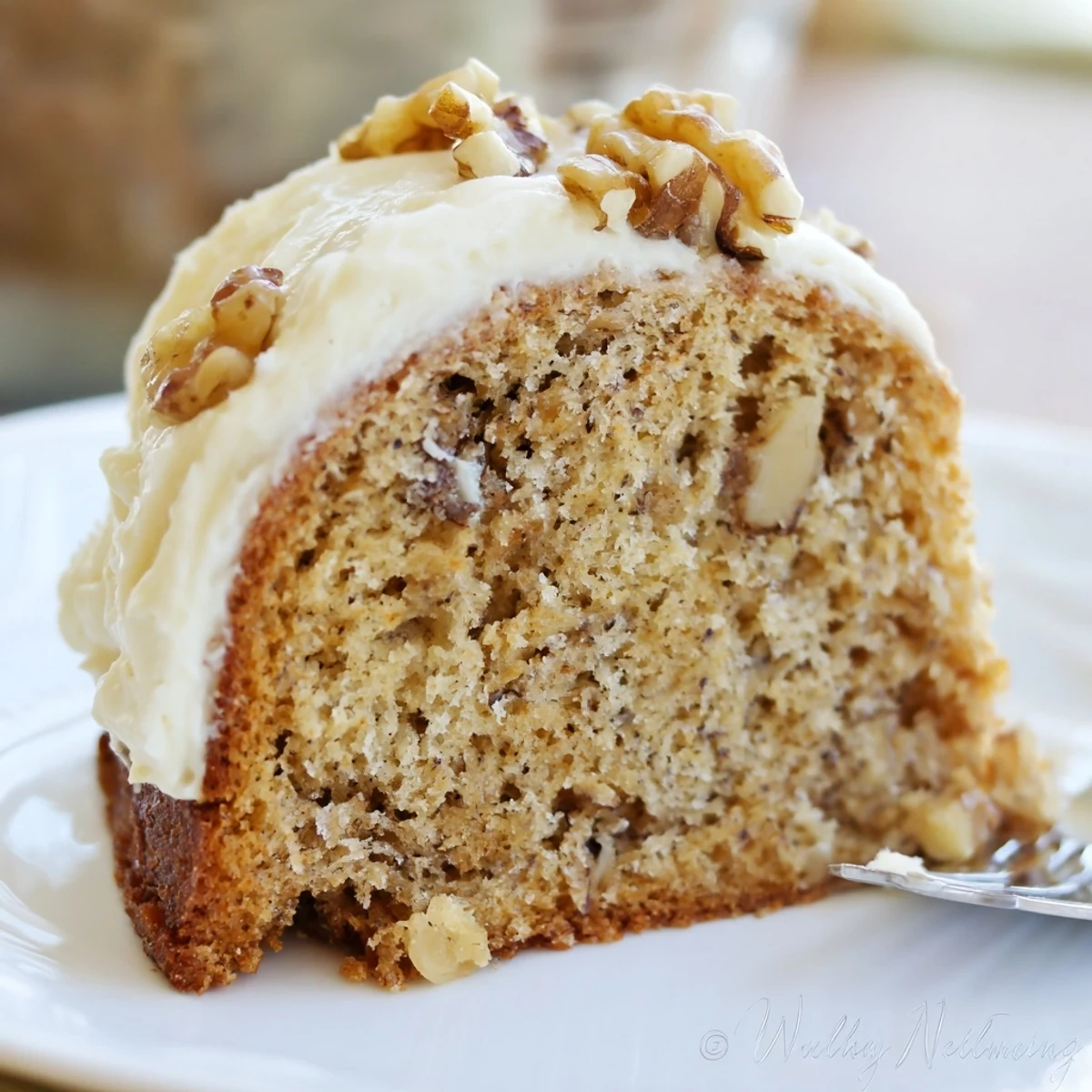 Warm banana cake served on a plate beside a steaming coffee cup