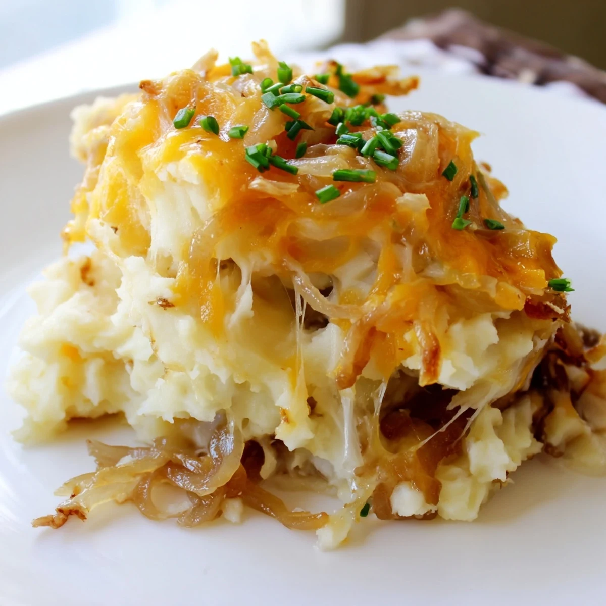 Creamy cheesy onion mashed potato casserole layered with sweet caramelized onions in a rustic baking dish